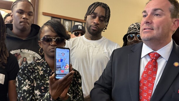 Following a May 29 press conference, Whitney Brown-Tune holds up a cell phone showing her late daughter, Jaleeyah Tune, dancing on TikTok. A bill bearing Jaleeyah's name sponsored by Rep. John Bell (right) that is meant to stiffen laws for gang members who give guns to minors is working through the General Assembly