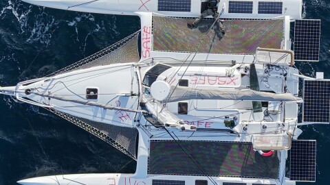 A crew member of the Canadian Coast Guard Ship Sir Wilfrid Laurier marks the word "SAFE" in red paint across the hull and cabin top of the the sailing vessel Mizuya before leaving it adrift in the North Pacific Ocean on June 19.