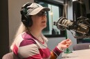 Woman wearing a cap and striped shirt gestures and talks at a microphone