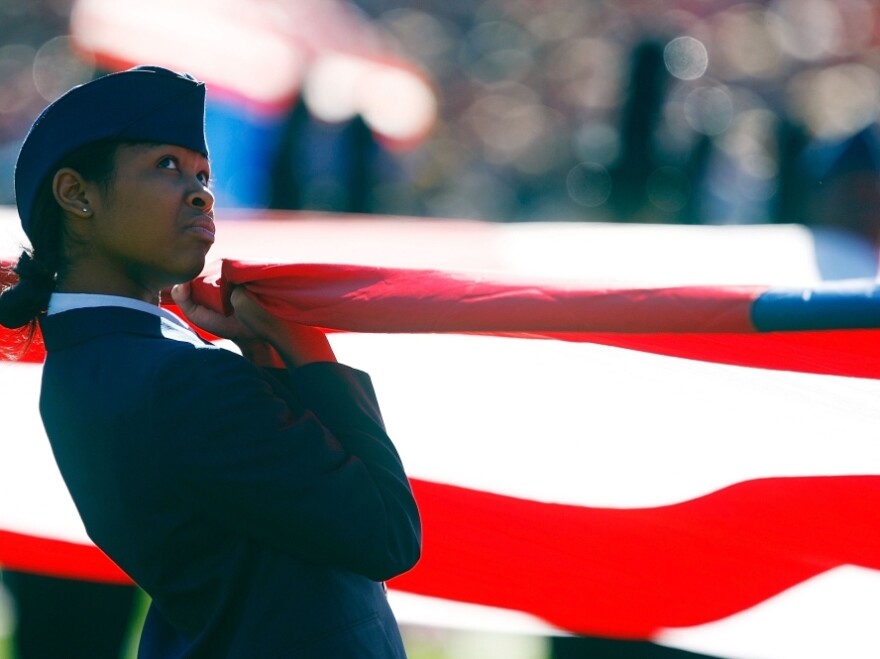 An ROTC member opens an American flag on the field prior to the start of a college football game. President Obama asked in his State of the Union address for renewed partnership between ROTC recruiters and schools.