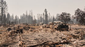 Dozens of houses are seen destroyed in a residential neighborhood as crews begin to check the area after a wildfire hit the northern part of Spokane, Wash., Tuesday, Aug. 4, 2026. (AP Photo/Lindsey Wasson)