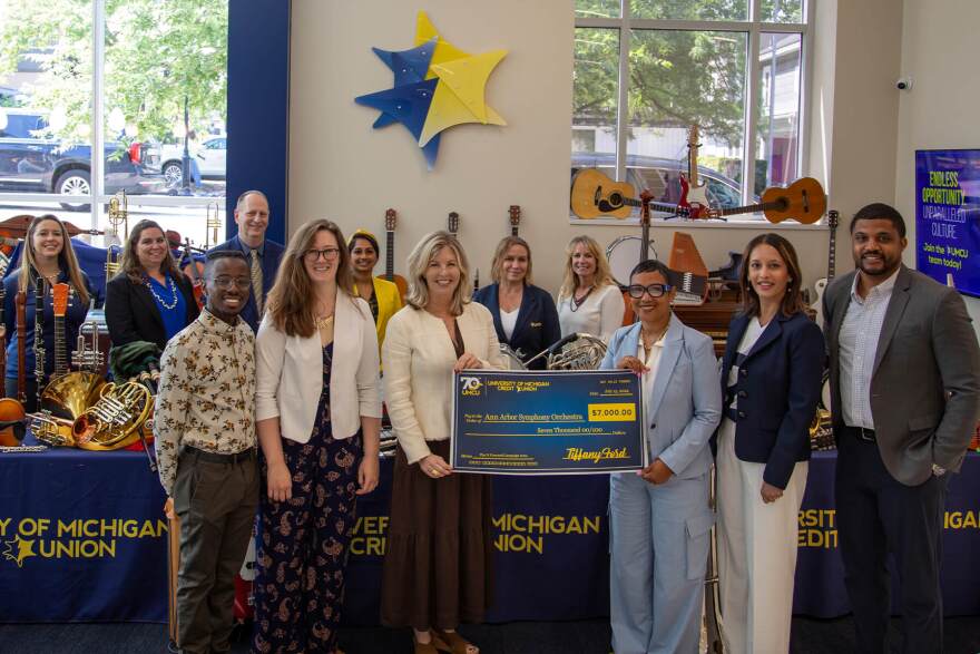 A2SO Executive Director Sarah Calderini (center) receives a donation from the University of Michigan Credit Union.