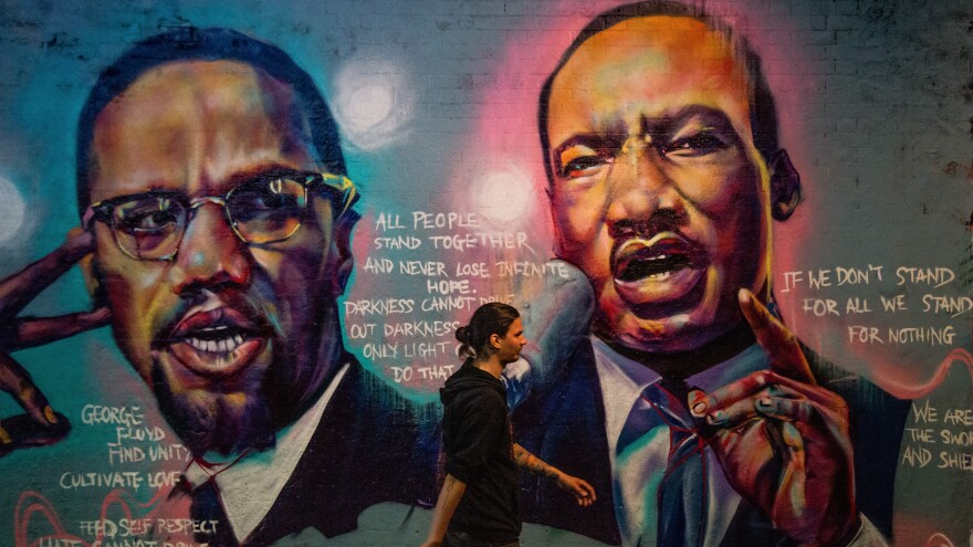 A man walks past a mural of Malcom X and Martin Luther King Jr. in London.