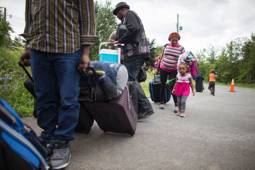 A long line of asylum-seekers waits to cross the Canada-U.S. border near Champlain, N.Y., on Sunday. The spike in new arrivals has overwhelmed existing Canadian facilities, and temporary housing is being arranged or assembled in Montreal and along the border.
