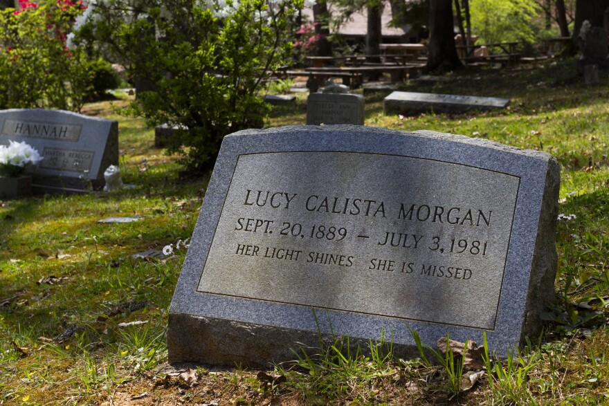 A close up of the headstone in a cemetery for Lucy Calista Morgan reads Her light shines, She is missed.