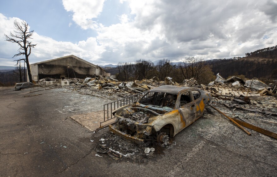 A charred car and the remains of the Swiss Chalet Hotel are pictured after being destroyed by the South Fork Fire in the mountain village of Ruidoso, N.M., Saturday, June 22, 2024. Authorities said a lightning strike caused the larger of two wildfires that killed at least two people and destroyed or damaged more than 1,400 structures in New Mexico.