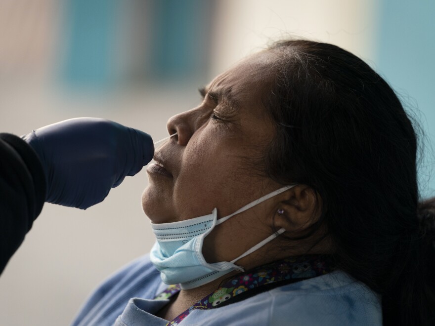 Leticia Lopez gets her sample collected for a COVID-19 test at a pop-up testing and vaccination site outside a swap meet in Los Angeles, Wednesday, Dec. 15, 2021.