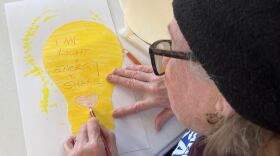 A State College resident decorates a paper lightbulb that will become part of the "Illuminating Hope" art installation.