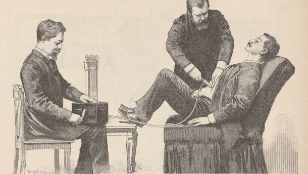 An antique illustration of three men with facial hair out of the 1800s. The man on the left is sitting in a chair, holding a box in his lap and turning a crank on the box's side. On the righthand side of the illustration, one man is sitting in a fabric chair, leaning back with his eyes closed and his feet resting on a table in front of him with his knees bent at a 90 degree angle. The third man is holding a metal tube on the seated man's abdomen. The metal tube is connected by a wire to the box that the man on the left is cranking.