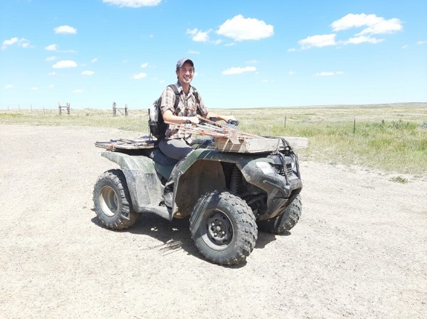 Man sitting on an ATV on a dirt road.