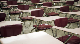 Rows of red school chairs placed in an empty classroom.