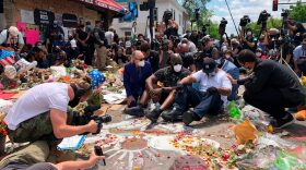 Terrence Floyd (C), sits as people gather at the site where his brother, George Floyd, died in Minneapolis, Minnesota. - 