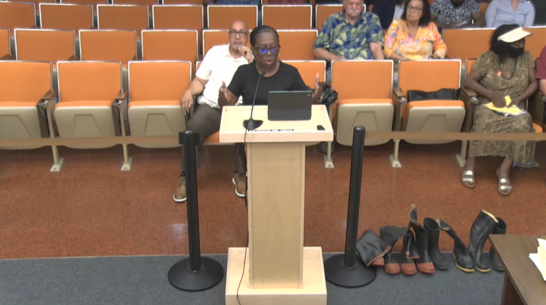 Cynthia Slater, 68, speaking at the Daytona Beach City Council meeting a week after Hurricane Ian flooded her Midtown home. On her right, are four pairs of wading boots. Slater bought each pair after a storm flooded out her home, which has happened four times in less than 20 years.