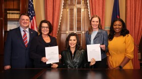 Governor Gretchen Whitmer, flanked by House and Senate leaders, presents the signed fiscal year budget.