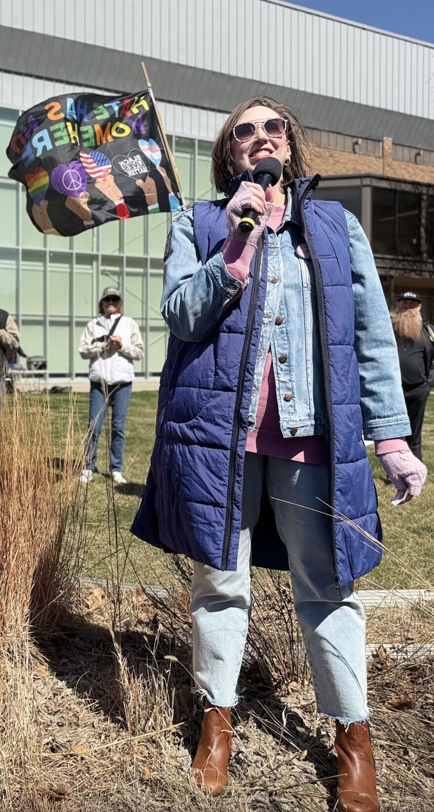 A pretty woman with a brunette bob haircut is smiling and holding a microphone.
