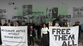 FILE - Demonstrators hold signs with images of environmental defenders during the COP29 U.N. Climate Summit, Nov. 20, 2024, in Baku, Azerbaijan.