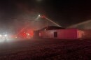 Firefighters on a big ladder spray water onto a business on fire