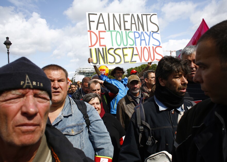 Protesters in Paris, one carrying a banner declaring "Slackers of all countries Unite," march against President Emmanuel Macron's overhaul on Tuesday.