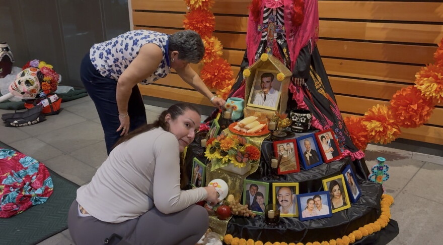 Alma Trevino sets up an ofrenda, or altar, honoring her father and other relatives on Oct. 30, 2026, at Naples Botanical Garden in Naples, Fla. Her display includes her nephew, grandparents, aunts and uncles from both sides of her family, with her father at the center.
