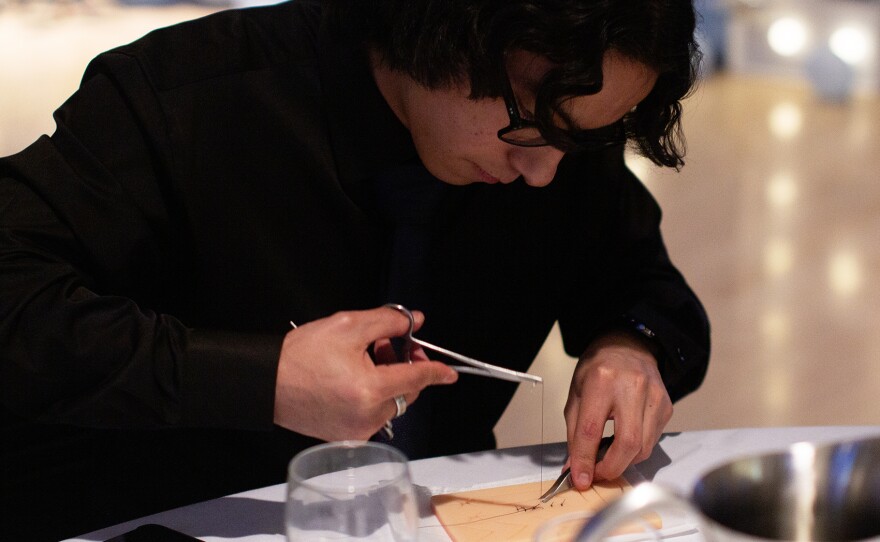 Samm Hoptowit, a Running Start student, bends over a suturing practice skin as he threads a needle through to make stiches on Monday, April 13 at the Pacific Northwest Pre-Health Spring Symposium at Washington State University. Hoptowit, who is Native American, says he's interested in going into general surgery and working in a tribal community in the future.