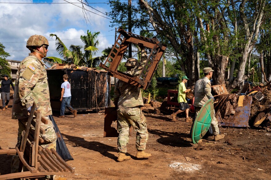 Hawaii National Guard soldiers and volunteers carry flood-damaged debris at a temporary dump site, Tuesday, March 24, 2026, in Haleʻiwa, Hawaiʻi. (AP Photo/Mengshin Lin)