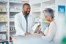 Smiling pharmacist and woman at counter with a bag of prescription drugs pills. 