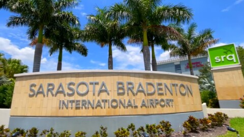 Sign says Sarasota Bradenton International Airport with palm trees in the background