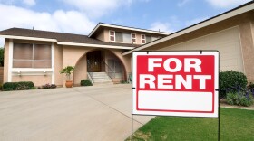 A for rent sign in front of a large home.