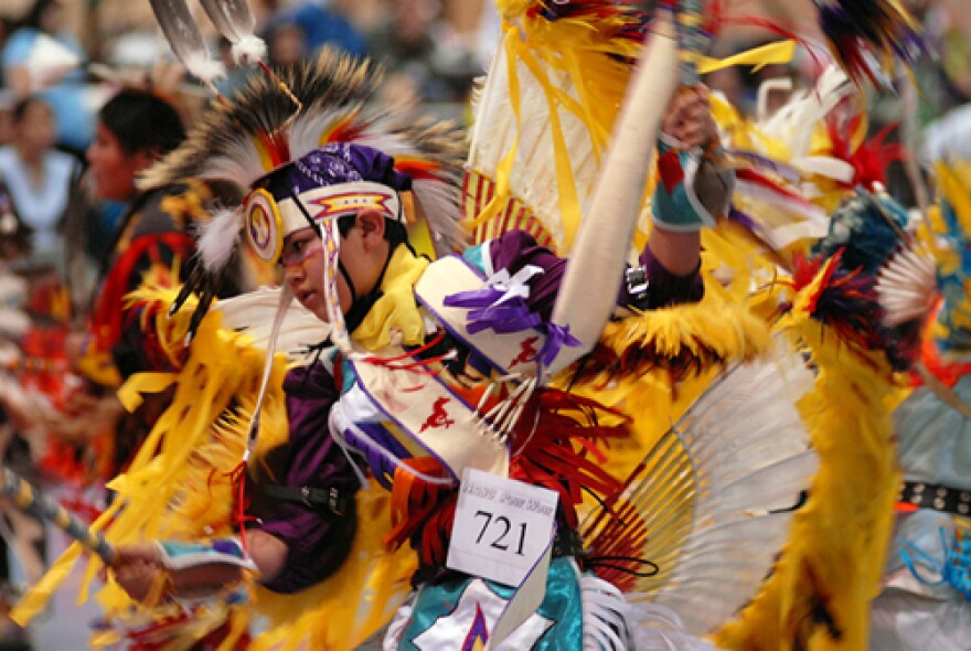 A Native American dancer in full regalia competing in a pow wow dance competition.