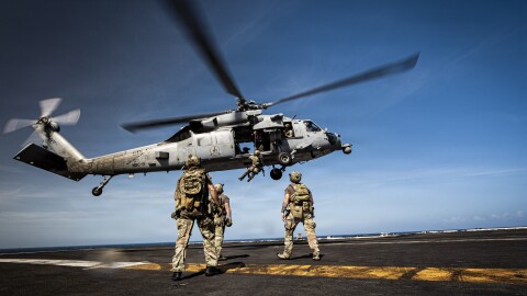 U.S. Coast Guard tactical team members are hoisted into an MH-60S Sea Hawk helicopter on the aircraft carrier USS Gerald R. Ford.