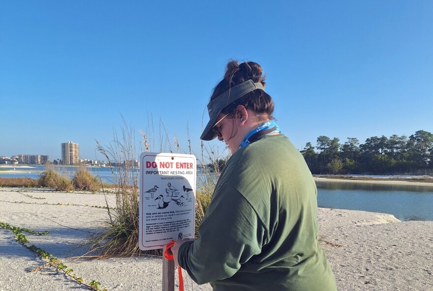 Woman on beach stands near do not enter important nesting area sign