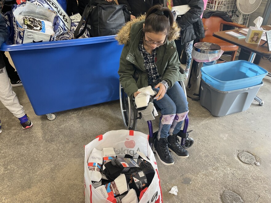 Carroll Middle School student Piper Yager drops a few pairs of socks into a bag inside the Rescue Mission on Wednesday, February 8, 2023.