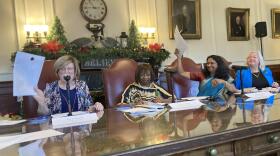 Four people hold up pieces of paper to cast electoral votes in the New Hampshire State House.