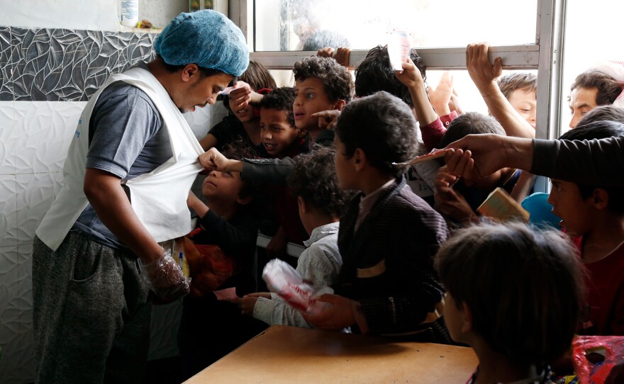 Yemeni children from families who are affected by the war talk to a worker to receive their lunch meals at a charitable center in April. Tens of thousands of the country's people are starving to death and another 5 million are on the brink.