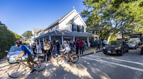 Cyclists and drivers of automobiles pass by the scene at St. Andrew’s Parish House in Edgartown, Massachusetts, where dozens of migrants from Venezuela were transported from the South to Martha Vineyard. 
