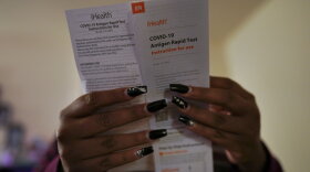 Danielle Mitchell reads directions before giving her daughter, Brooklynn Chiles, 8, a COVID-19 antigen rapid test at home in Washington, Sunday, Jan. 9, 2022. Proof of a negative test is required for Brooklynn to attend third grade classes at Rocketship Rise Academy Public Charter School in Washington.