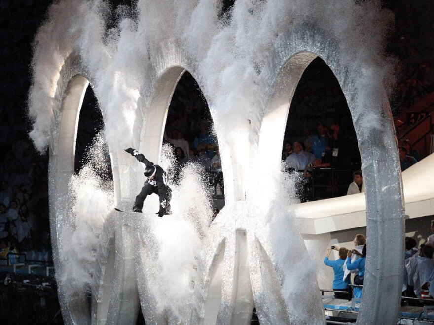 A snowboarder jumps through the Olympic rings during the opening ceremony.