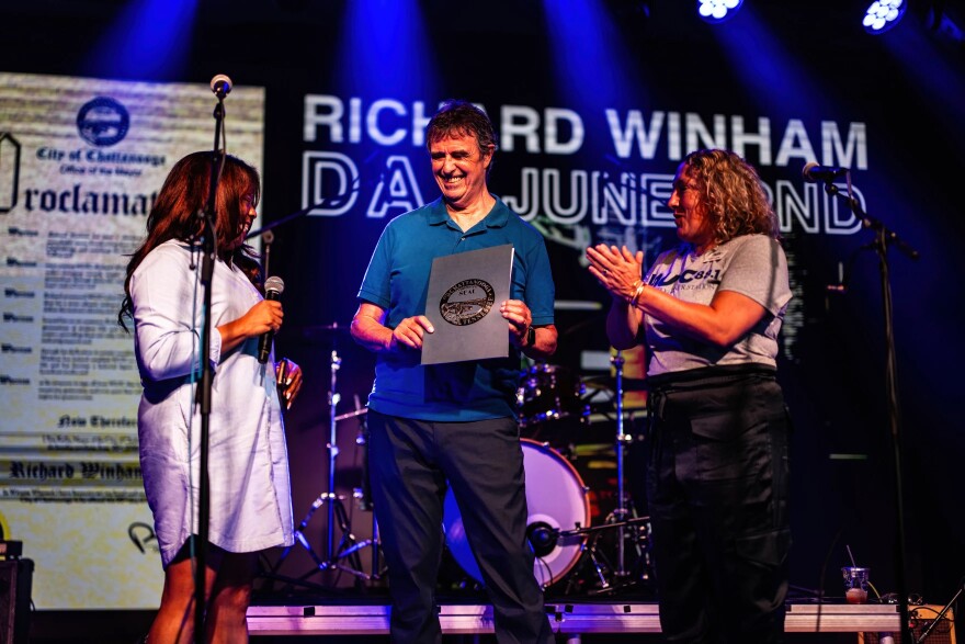 Richard Winham, center, receives a special proclamation by Chattanooga Mayor Tim Kelly at his retirement concert - declaring June 22 as "Richard Winham Day." On stage with Richard: Carmen Davis of the City of Chattanooga, at left - and Susan Lazenby of WUTC, at right.