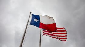 The Texas and U.S. flags wave outside the John H. Reagan State Office Building. 