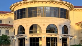 A cream colored rotunda by a gray brick sidewalk