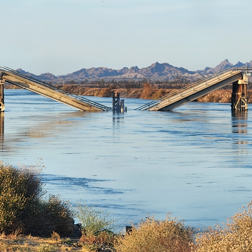 A cement and wood bridge broken in the middle and fallen into the water