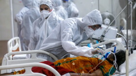 A health worker tries to adjust the oxygen mask of a patient at the BKC jumbo field hospital, one of the largest COVID-19 facilities in Mumbai, India, Thursday, May 6, 2021.