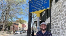 Kingston historian Taylor Bruck stands under the state placard honoring the intersection — a surprisingly popular local attraction.