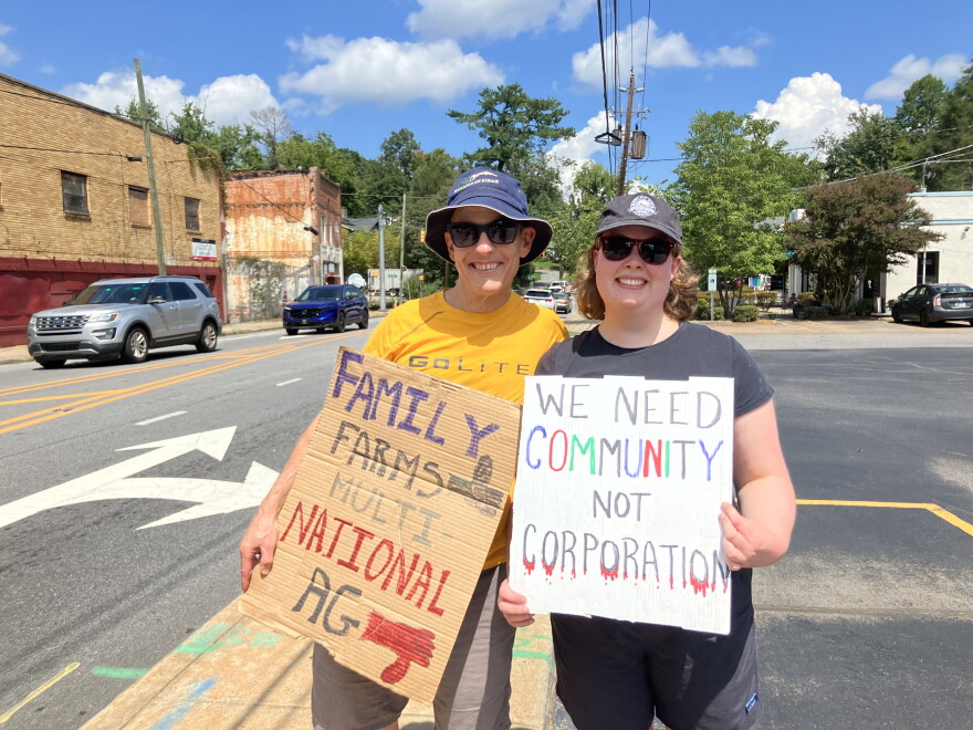 Mitch and Anne Elise Russell hold signs during a demonstration on Merrimon Avenue in Asheville Saturday, August 29, 2026.