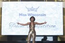 Miss Wisconsin pageant winner, Willow Newell, is pictured wearing a gold outfit, her arms outstretched, as she performs a song during the talent competition.
