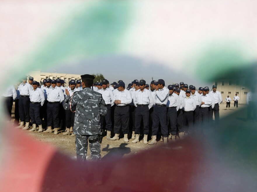 Iraqi police recruits are seen through a banner during a 2009 graduation ceremony for members of the Sons of Iraq at a police training center in southern Baghdad. The government agreed to either integrate the militiamen into the armed forces or give them civilian jobs.