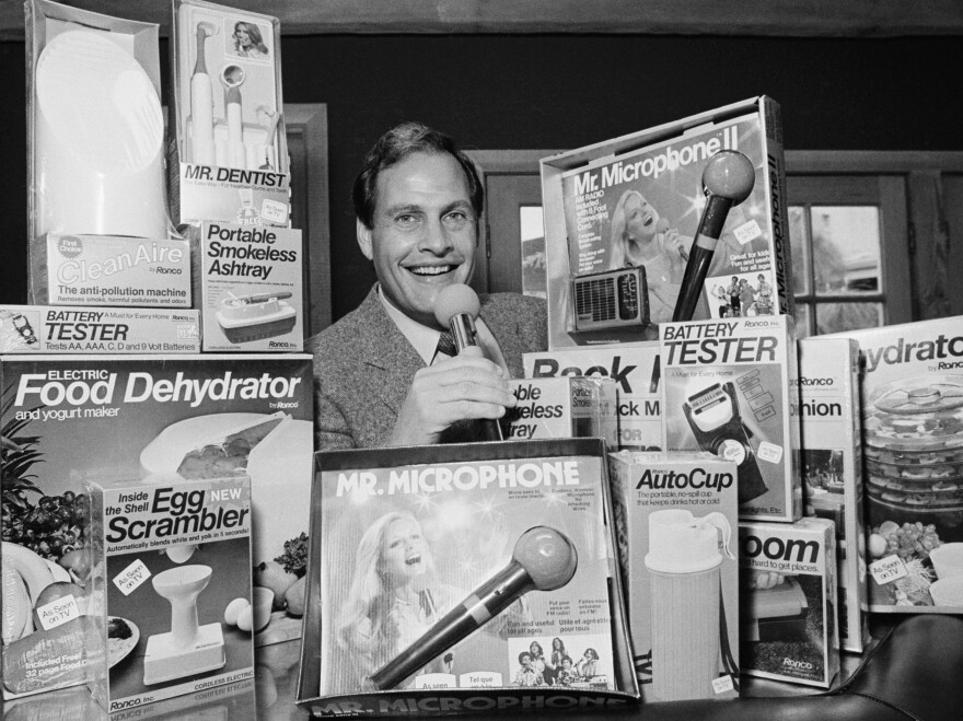 In this 1982 file photo, Ron Popeil, the man behind those late-night, rapid-fire television commercials that sell everything from the Mr. Microphone to the Pocket Fisherman to the classic Veg-a-Matic, sits surrounded by his wares in his office in Beverly Hills, Calif. Popeil died Wednesday, July 28, 2021 his family said.