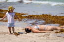 A woman lays near the seaweed lined seashore at the South Pointe Park Pier.