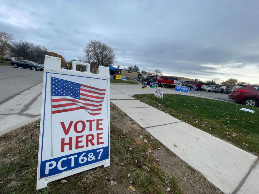 a vote here sign sits in front of a polling place