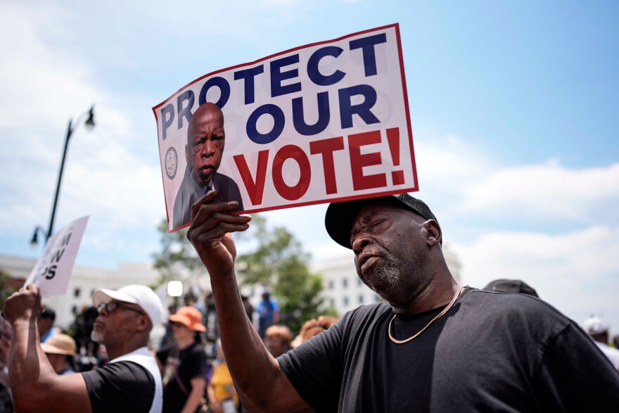 Aaron McGuire sings a spirtual song and holds a sign reading "Protect our vote" during a voting rally, Saturday, May 16, 2026, in Montgomery, Alabama.